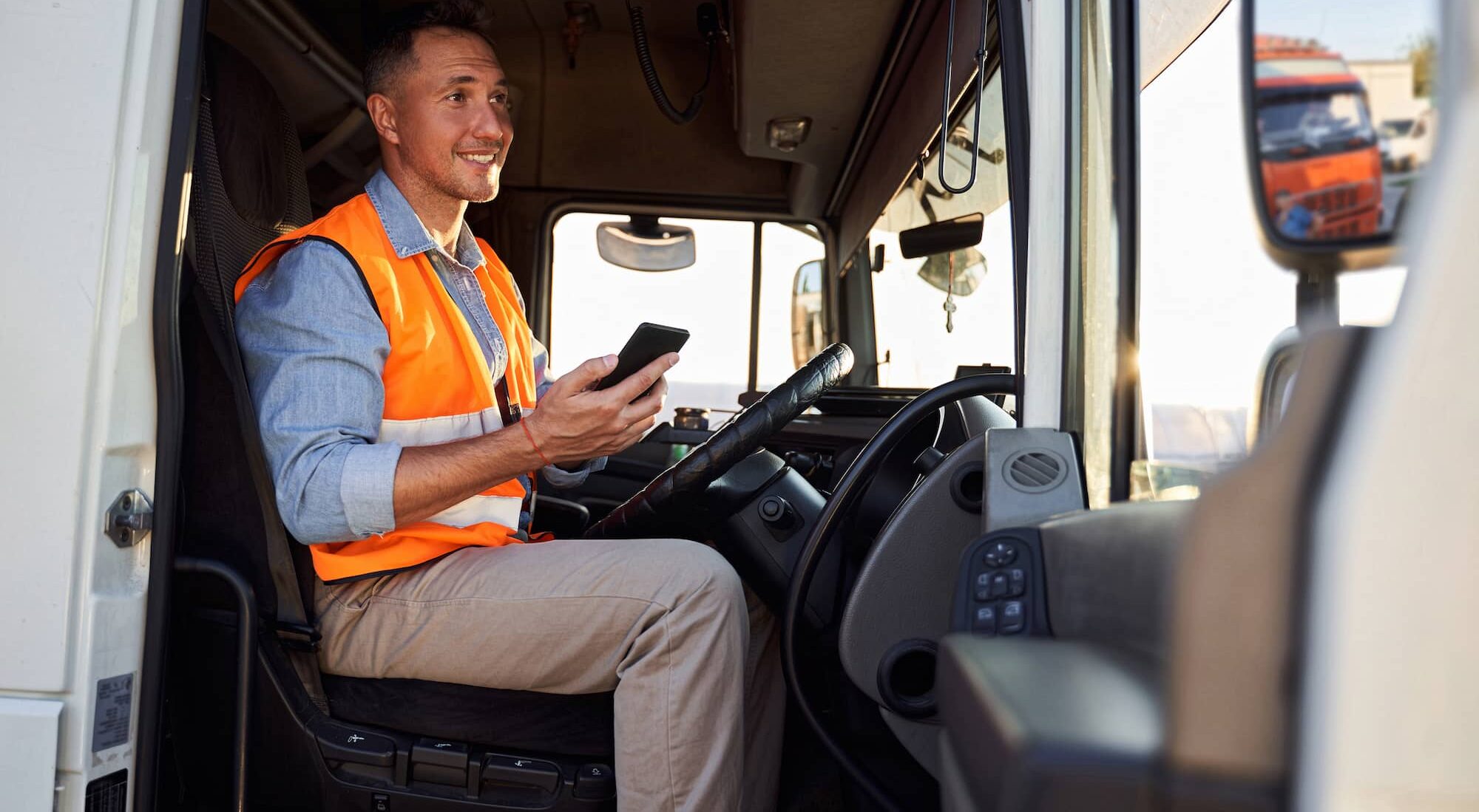 Man sat in lorry smiling with phone out